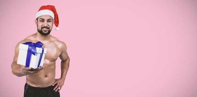 Composite image of muscular man in santa hat