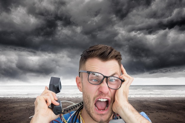 Composite image of portrait of frustrated computer engineer screaming while on call in front of open cpu