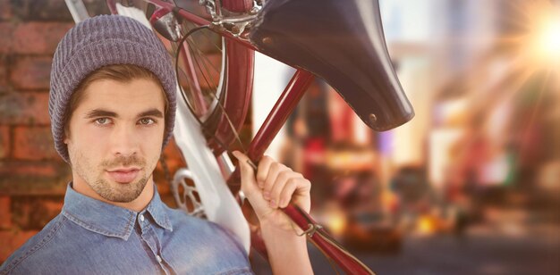 Composite image of portrait of hipster carrying bicycle