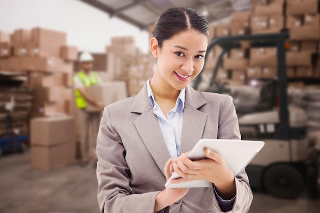 Composite image of portrait of a smiling businesswoman using a tablet computer