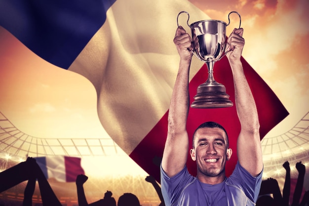 Composite image of portrait of smiling rugby player holding trophy