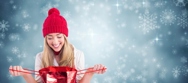 Composite image of pretty blonde opening gift bag