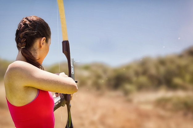 Composite image of rear view of sportswoman doing archery on a white background