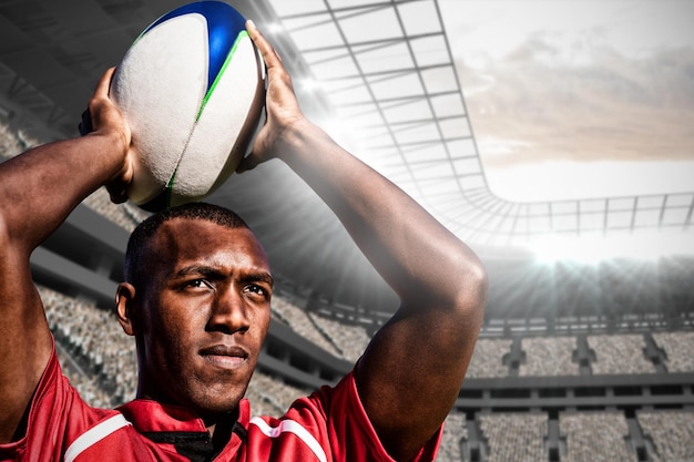 Composite image of rugby player holding football above head