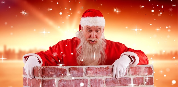 Composite image of santa claus peeking over wall