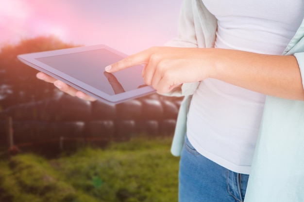 Composite image of woman using tablet pc against rural landscape