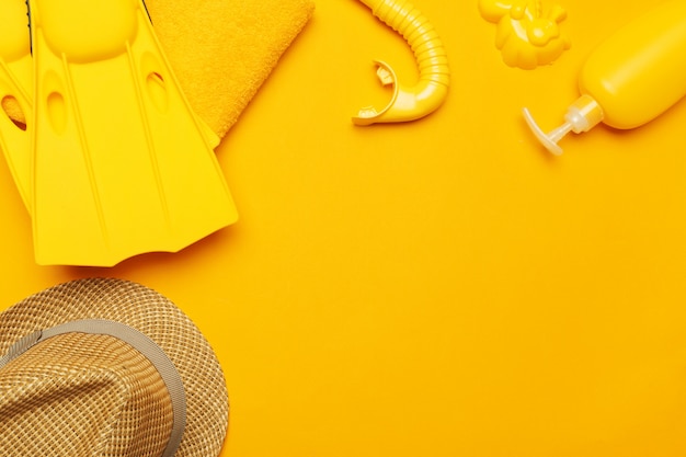 Composition of beachwear and accessories on a yellow 