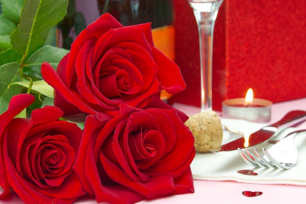 A composition of a beautiful bouquet of roses, glasses and a bottle of champagne creates a romantic card or poster. The concept of st valentine's day, Mother's Day, March 8.