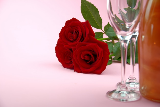 A composition of a beautiful bouquet of roses, glasses and a bottle of champagne creates a romantic card or poster. The concept of st valentine's day, Mother's Day, March 8.