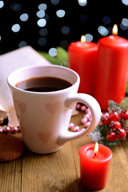 Composition of book with cup of coffee and Christmas decorations on table on dark background