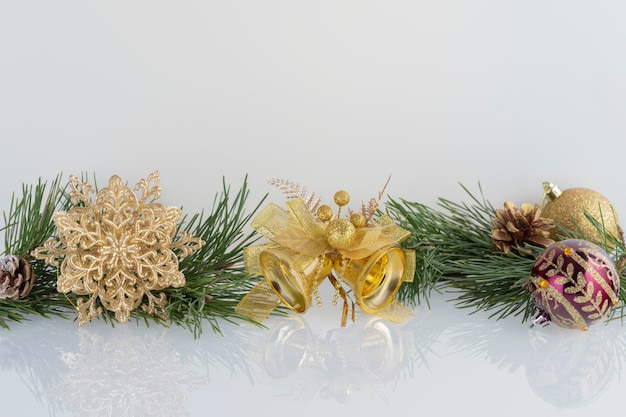 Composition of Christmas decoration gold baubles, snowflake, bells and cones with branches of pine