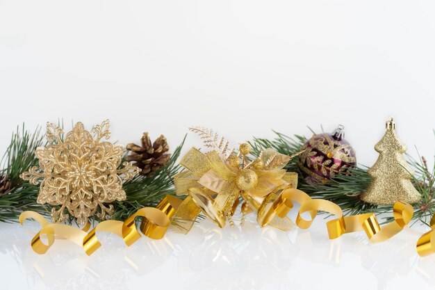 Composition of Christmas decoration gold baubles, snowflake, bells and cones with branches of pine