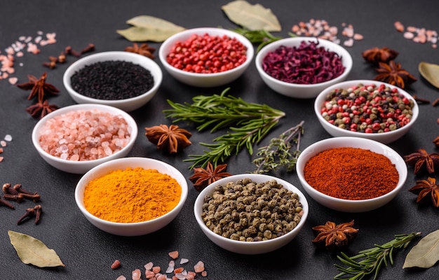 Composition consisting of a variation of several types of spices in white ceramic bowls on a textured concrete background