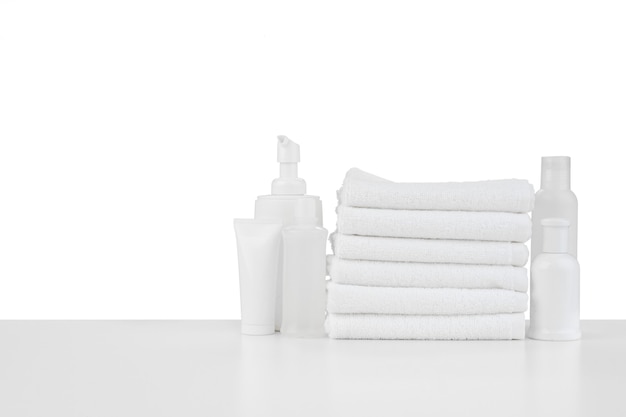 Composition of cosmetic bottles and towels isolated on white