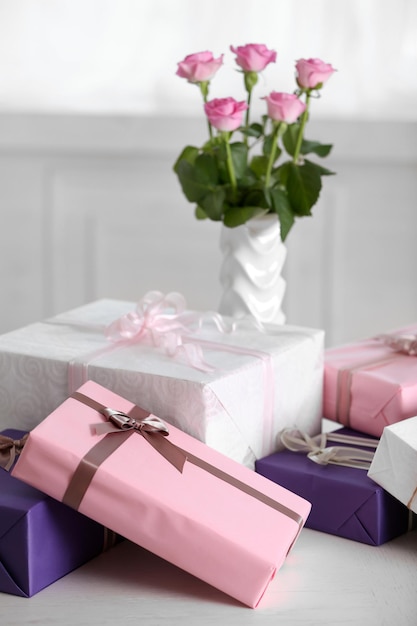 Composition of cute gift boxes and roses on white table