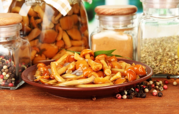 Composition of delicious marinated mushrooms oil and spices on wooden table on bright background