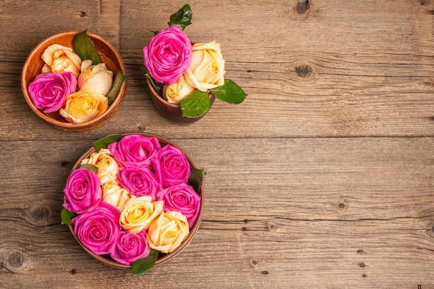 Composition of fresh multicolored roses in kitchen utensil. The festive concept for Weddings, Birthdays, March 8th, Mother's, or Valentine's Day. Greeting card, flat lay, vintage wooden table