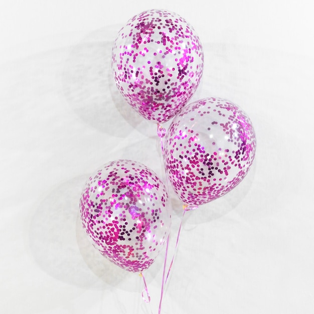 Composition of fuchsia confetti balloons on white background. Gift for boys and girls