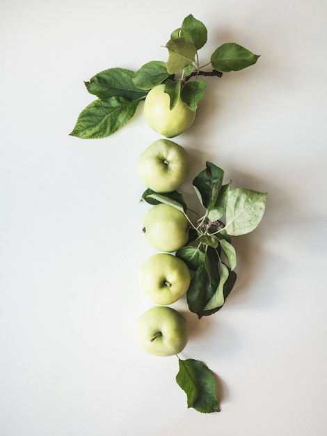 Composition of green apples and leaves on a white background. Wallpaper of fruits.Top view, flat lay.