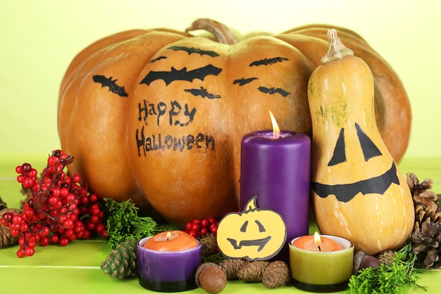 Composition for Halloween with pumpkins and candles on wooden table on color background