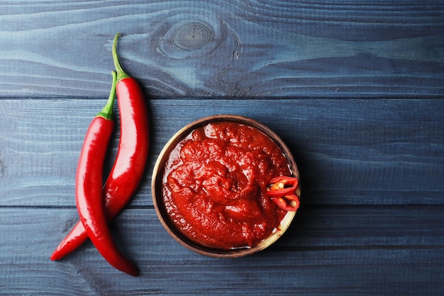 Composition of hot tomato sauce in a wooden bowl on a blue wooden background