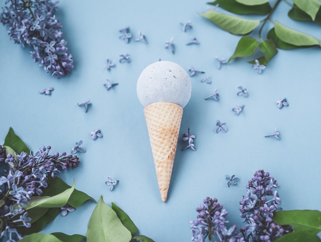 Composition of ice cream cone with bath ball. Flat Lay. Top View. Lilac flowers