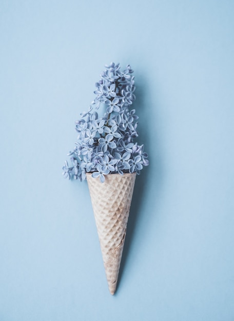 Composition of ice cream cone with purple lilac flowers. Flat Lay. Top View. Creative summer concept