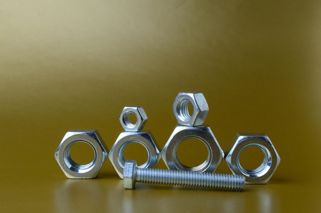 Composition of new nuts and bolts of different sizes on a yellow background