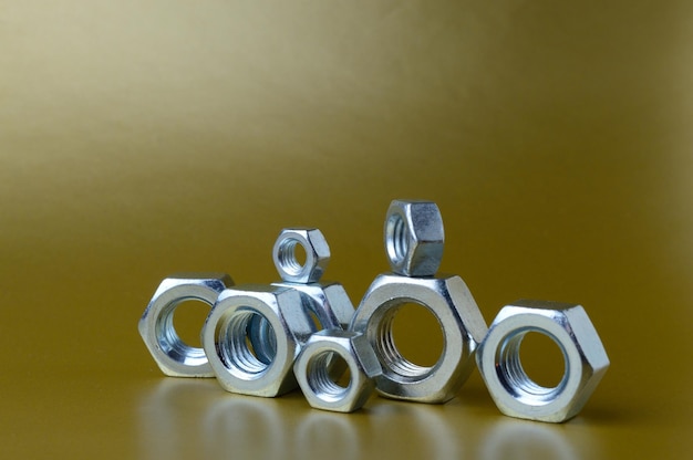 Composition of new nuts and bolts of different sizes on a yellow background