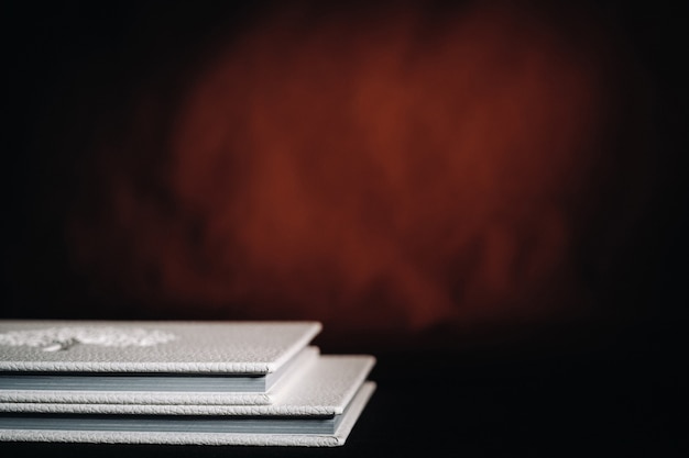 Photo composition of photo books in natural white leather of different sizes. the white paper on a dark background.