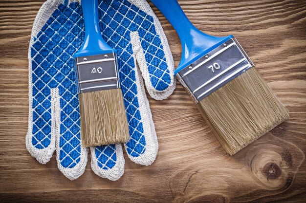 Composition of safety gloves paint brushes on wooden board construction concept