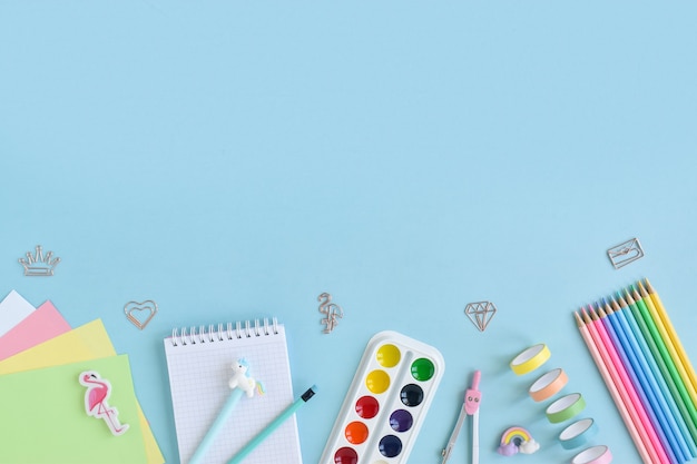 Composition of school supplies in pastel colors on a light blue surface