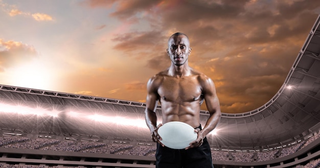 Composition of shirtless male rugby player holding rugby ball over sports stadium