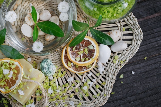 Composition of spa treatment with green salt and soap on wooden surface