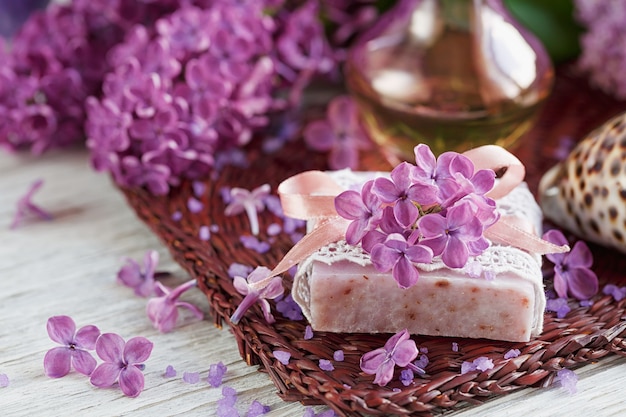  composition of spa treatment with natural sea salt,  aromatic oil and lilac flowers on white wooden