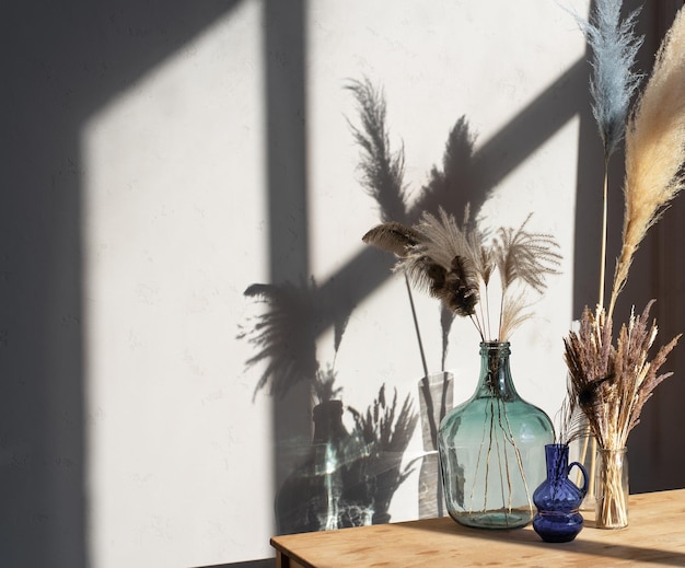 A composition of vases with dried flowers of a different type on a wooden table in light room interi