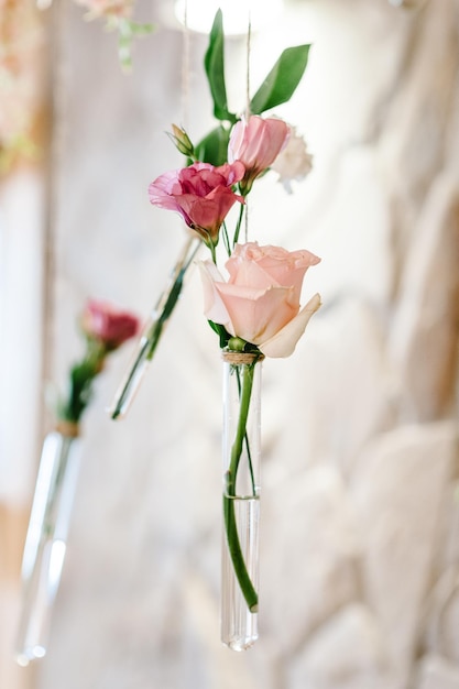 Composition of violet pink flowers greenery herbs in glass vases and bulbs hanging on a wedding ceremony on photo zone Wedding ceremony