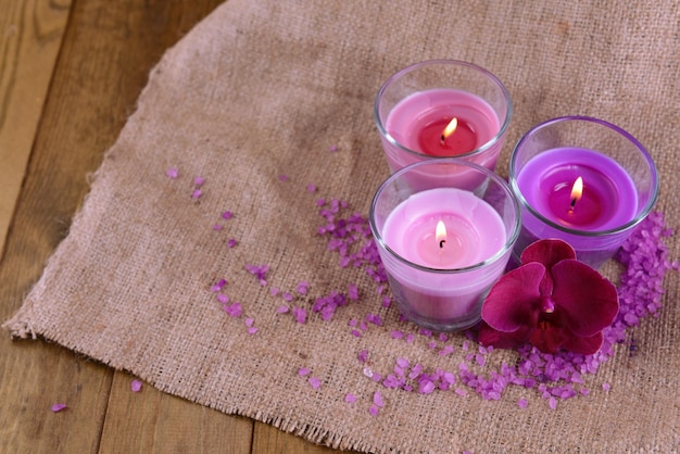 Composition with beautiful colorful candles sea salt and orchid flowers on wooden background