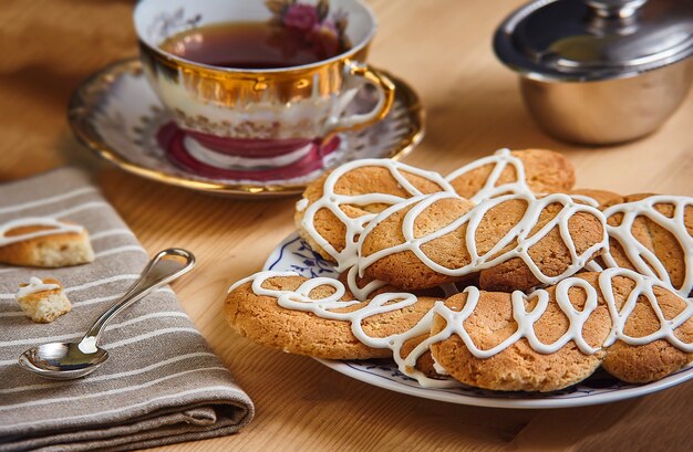 Composition with biscuits on a wooden table with sugar and teaspoon and cup of tea