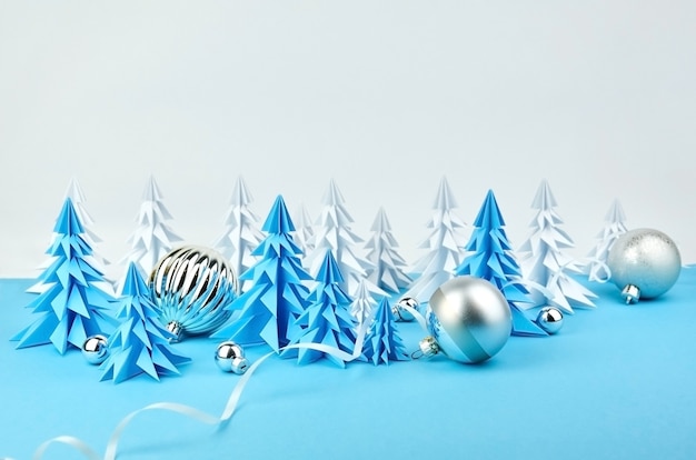 Composition with blue and white paper Christmas trees and ball decorations