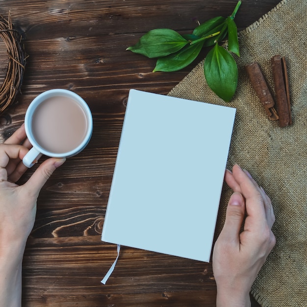 Composition with book, hand , cup of coffee and leaves