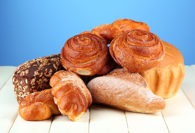 Composition with bread and rolls on wooden table on color background