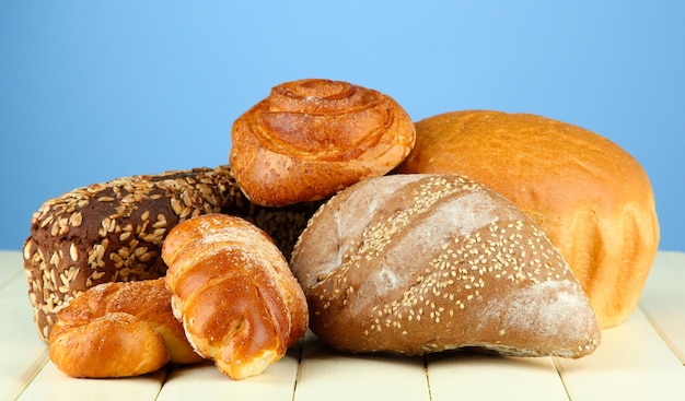 Composition with bread and rolls on wooden table on color background