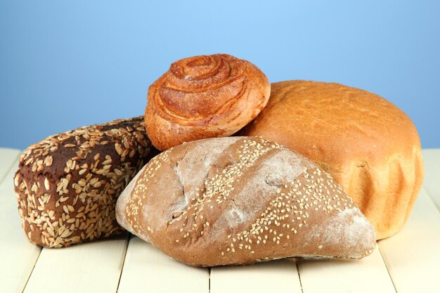 Composition with bread and rolls on wooden table on color background