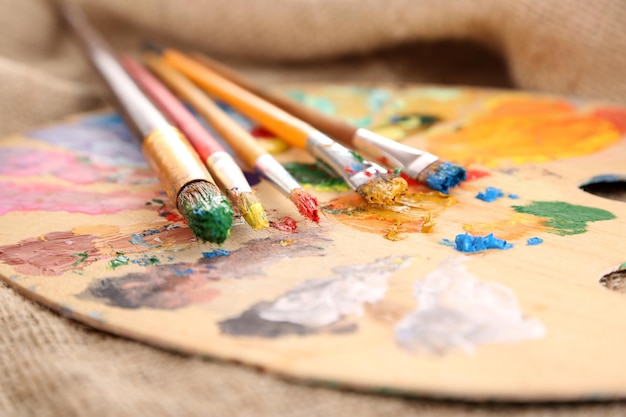 Composition with brushes on used wooden palette on wooden background