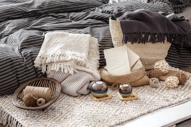 Composition with candles, knitted elements and other decor details in the bedroom.