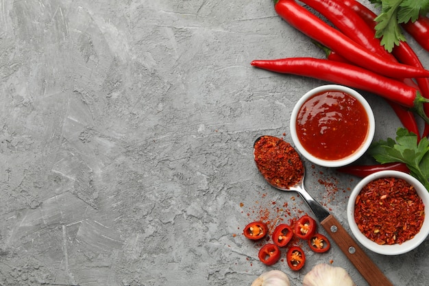 Composition with chilli pepper, powder spice, garlic and sauce on gray