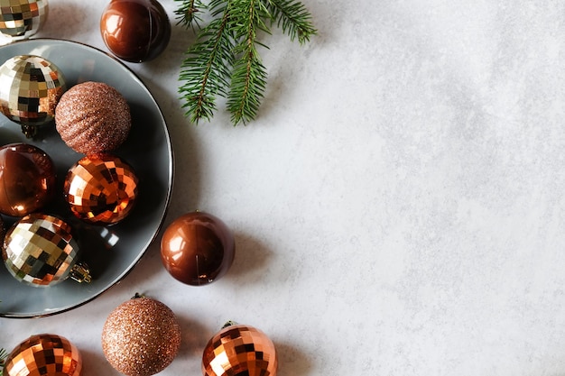 Composition with Christmas decorations on plate and christmas tree on grey concrete background