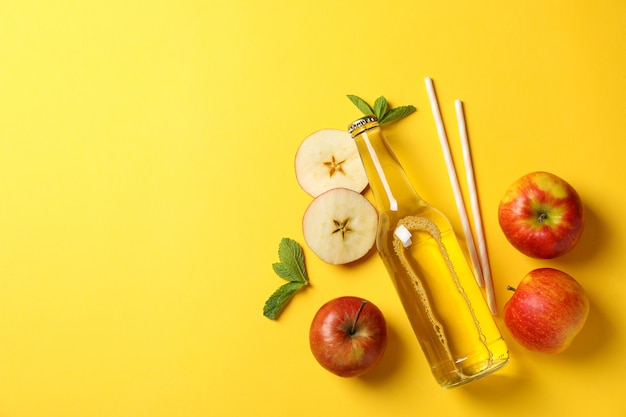 Composition with cider, apples and straws on yellow