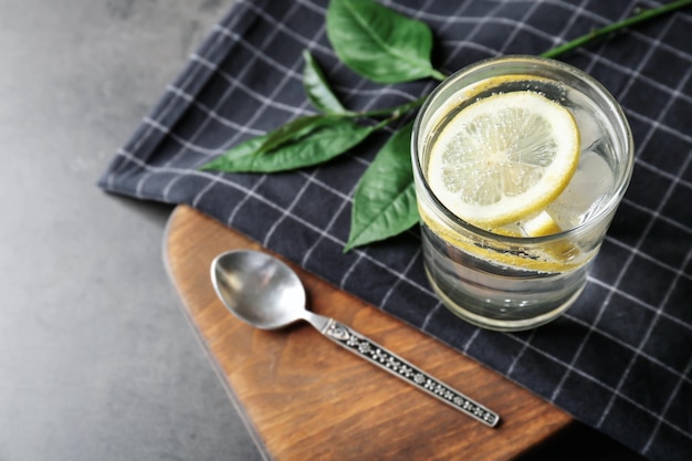 Composition with cold lemon water on grey table closeup